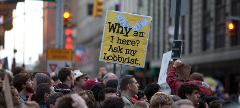 A protester holds a sign in Times Square by Geoff Stearns https://flic.kr/p/aw6XLr (CC BY 2.0)