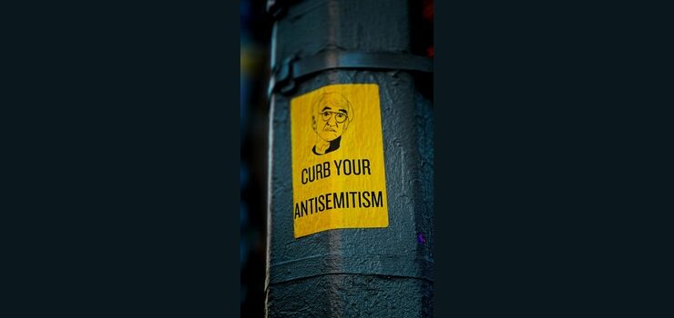 a sticker on the side of a pole that says curb your antisemitism by Jon Tyson, Unsplash licence, https://unsplash.com/photos/a-sticker-on-the-side-of-a-pole-that-says-curb-your-antisemit-iCP8fi7MX0c