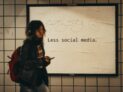 a woman standing in front of a sign that says less social media by Jon Tyson, unsplash license, https://unsplash.com/photos/a-woman-standing-in-front-of-a-sign-that-says-less-social-media-e1xl7iby_Ug